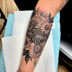 a woman's arm with sunflowers and harley davidson logo on the sleeve