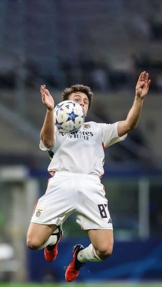 a soccer player jumping up in the air to catch a ball with his hands and head