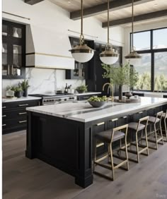 a large kitchen with black cabinets and white counter tops, gold accents on the island