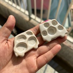 two pieces of white pottery in the palm of someone's hand with their fingers