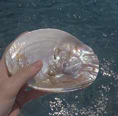 a person holding up a small glass bowl in the water with bubbles coming out of it