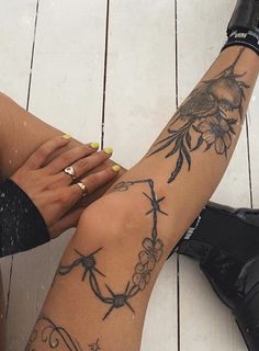 a woman's legs with tattoos on them sitting on a wooden floor next to an umbrella