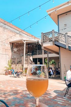 a glass of wine sitting on top of a table next to a brick floor covered patio