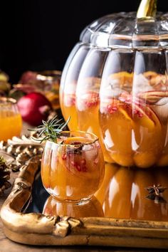 two glasses filled with liquid sitting on top of a table next to apples and spices