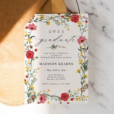 a white and red floral graduation party card on top of a wooden cutting board next to a pair of scissors