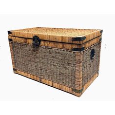 a large wicker trunk with black handles on the top and bottom, sitting in front of a white background