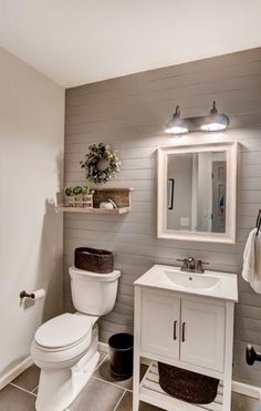 a white toilet sitting next to a sink in a bathroom under a mirror and lights