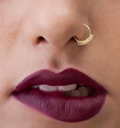 a woman's nose with a gold crescent piercing on top of her lip,