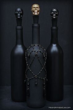 three black bottles with chains on them and a gold skull in the top right corner