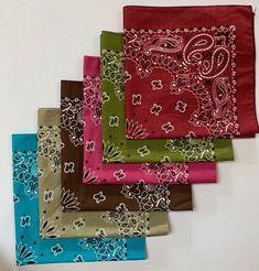 six different colored bandannas on a white table top with one folded up and the other folded down