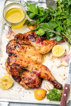 a chicken is sitting on a cutting board with lemons and parsley next to it