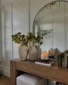 two vases filled with plants sit on a table next to a mirror and books