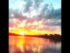 the sun is setting over water with clouds