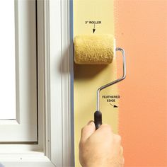 a person using a paint roller to paint a wall with orange and yellow colors on it