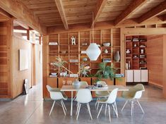 a dining room with wood paneling and white chairs around a table in front of a bookshelf