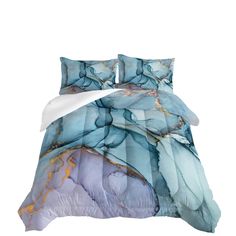 a bed covered in blue and white comforter with an abstract design on the cover