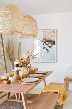 a dining room table with plates and bowls on it, next to an art piece