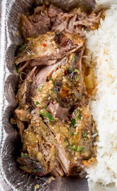 meat and rice in a foil container on top of a table with utensils