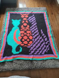 a crocheted rug on the floor with an image of a cat and fish