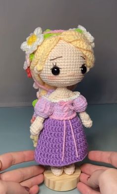 a crocheted doll is being held by two hands