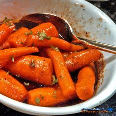 a white bowl filled with carrots covered in sauce