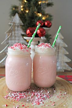 two glasses filled with white hot chocolate and sprinkles, on top of a table