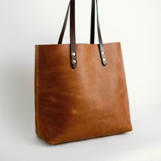 Meet your new everyday bag. Simple construction and soft lines make for a bag that'll never go out of style and will only get better with age. Premium Full-grain leather, robust stitching and solid brass hardware for a lifetime of service, guaranteed. -11" Shoulder Drop -Interior Accessory Pocket Dimensions: 14" x 13.5" x 6" Enjoy a complimentary, monogrammed Bag Tag. Simply place your monogram in the monogram box below. Everyday Satchel With Waxed Finish And Double Handle, Classic Everyday Shoulder Bag In Vegetable Tanned Leather, Classic Bags With Brass Hardware And Double Handle, Classic Vegetable Tanned Leather Shoulder Bag For Everyday, Leather Bags With Brass Hardware For Work, Classic Vegetable Tanned Leather Shoulder Bag, Everyday Brown Shoulder Bag With Brass Hardware, Classic Bags With Leather Lining And Oiled Leather, Classic Tote Bag With Leather Backing