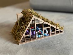 a small house with moss growing on the roof and several beads in front of it