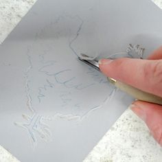 a person is cutting paper with a pair of scissors on top of the piece of paper