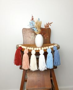 a wooden chair with tassels and a vase on top