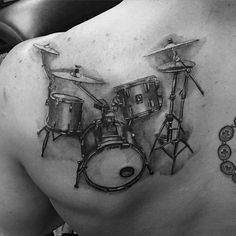 a man with a tattoo on his back has a drum set