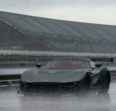 a silver sports car driving on a wet track in front of an empty bleachers