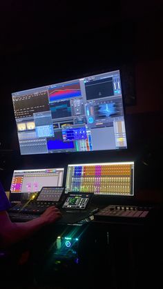 a man sitting in front of two computer monitors with sound mixing equipment on the desk