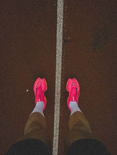 the feet of a person wearing pink shoes standing in front of a cross walk line