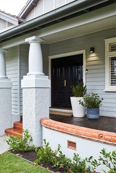 a white house with two large planters on the front porch