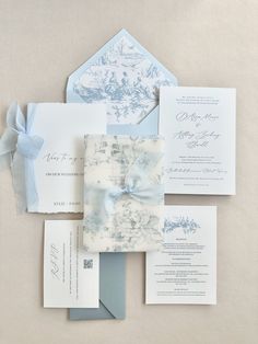 the wedding stationery is laid out on top of each other, including an envelope with a bow