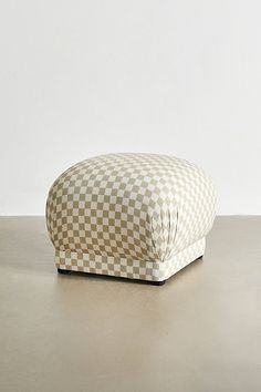 a white and brown checkered pillow sitting on top of a table next to a wall