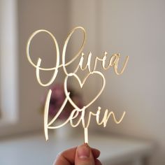 a person holding up a cake topper with the word love spelled in cursive writing