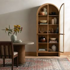 a room with a table, chairs and vases on the shelf next to it