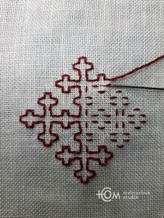 a cross stitched snowflake with red thread