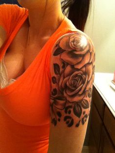 a woman in an orange shirt with a rose tattoo on her arm and shoulder is taking a selfie