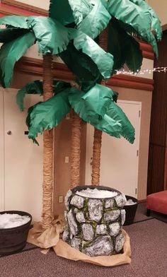 two palm trees made out of toilet paper and trash cans are sitting on the floor