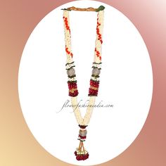 a necklace with beads and flowers hanging from it's side on a white circle