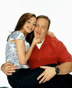 a man and woman sitting next to each other posing for a photo with their hands on their chins