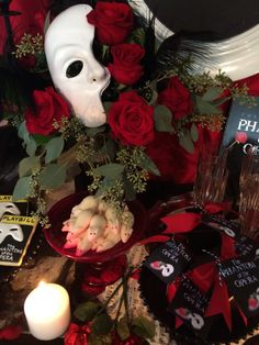 a table topped with red roses and a white mask