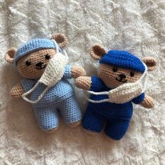 two crocheted teddy bears laying on top of a white blanket next to each other