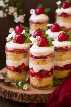 strawberry shortcakes with whipped cream and fresh strawberries in jars on a wooden tray