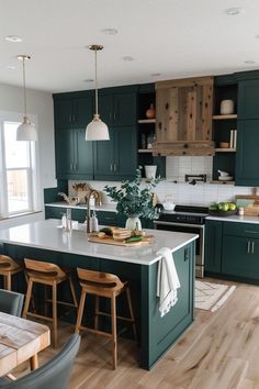 a kitchen with dark green cabinets and white counter tops, wooden flooring and stools