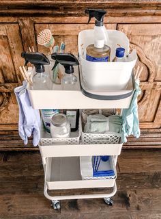 a bathroom cart with cleaning products and other items on it in front of a wooden cabinet