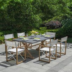 an outdoor dining table and chairs set up in the middle of a patio with trees behind it